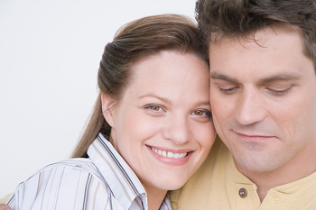 A woman and a man embrace. The woman is smiling toward the camera.