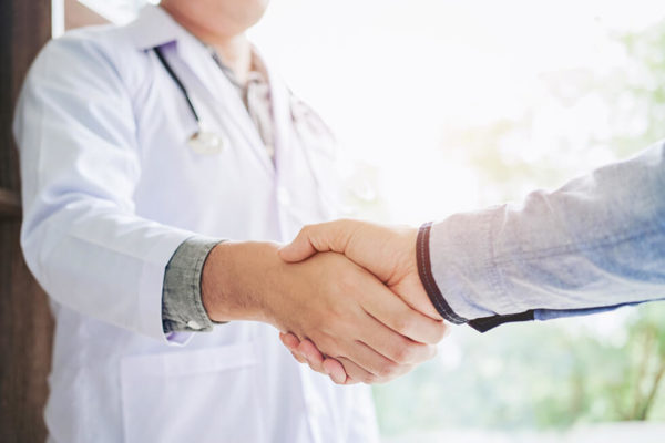 A doctor shakes hands with a male patient